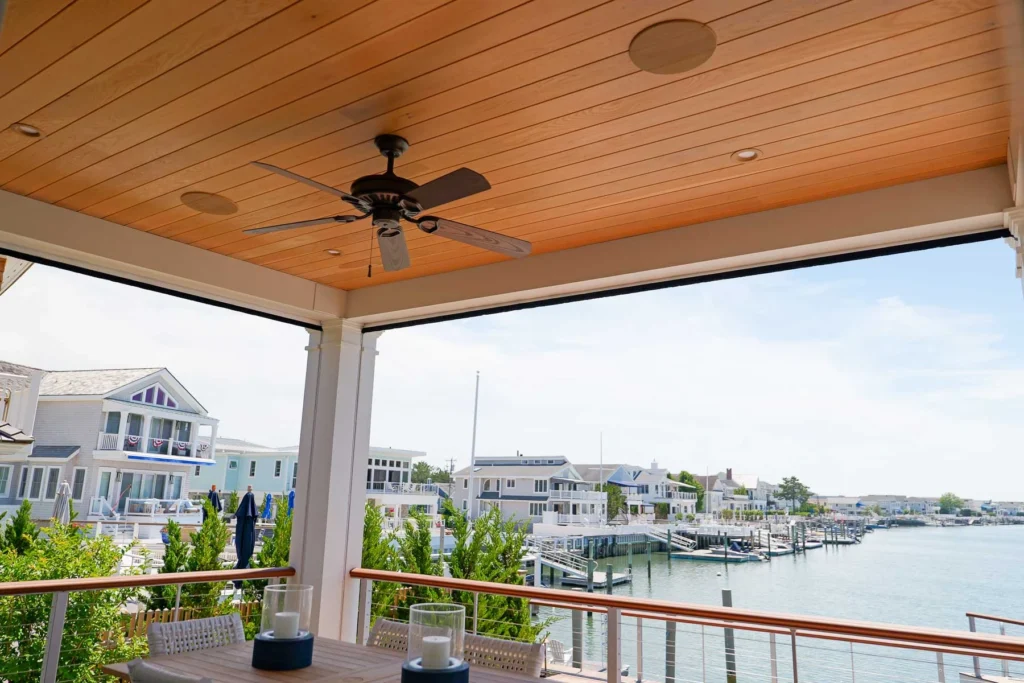 Bayfront covered porch at a Stone Harbor, NJ home with custom-painted exterior speakers flush-mounted into the wood ceiling, installed by Cooltronics.