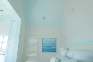 Primary bedroom in a Stone Harbor, NJ home showing the vaulted shiplap ceiling with a flush-mounted in-ceiling speaker, installed by Cooltronics.