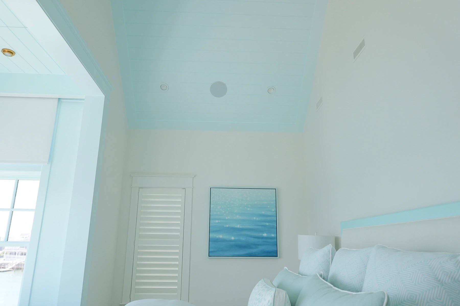 Primary bedroom in a Stone Harbor, NJ home showing the vaulted shiplap ceiling with a flush-mounted in-ceiling speaker, installed by Cooltronics.