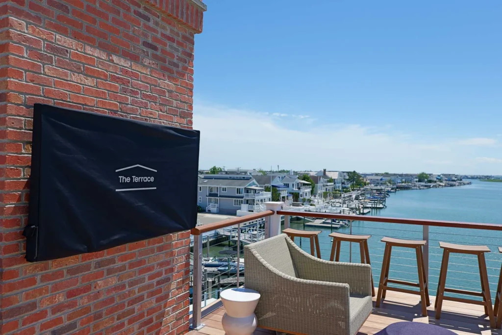 Samsung Terrace outdoor TV with weather cover on the rooftop deck of a Stone Harbor, NJ home, looking out over the marina, installed by Cooltronics.