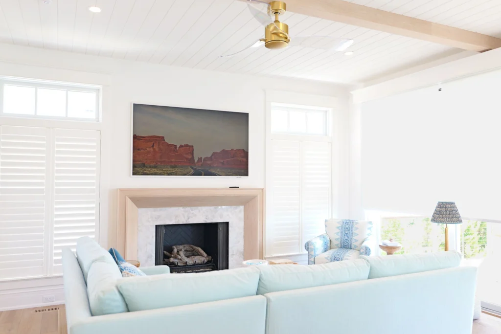 Samsung Frame TV displaying landscape artwork above the fireplace, with a Lutron motorized shade partially deployed, in a Stone Harbor, NJ home installed by Cooltronics.